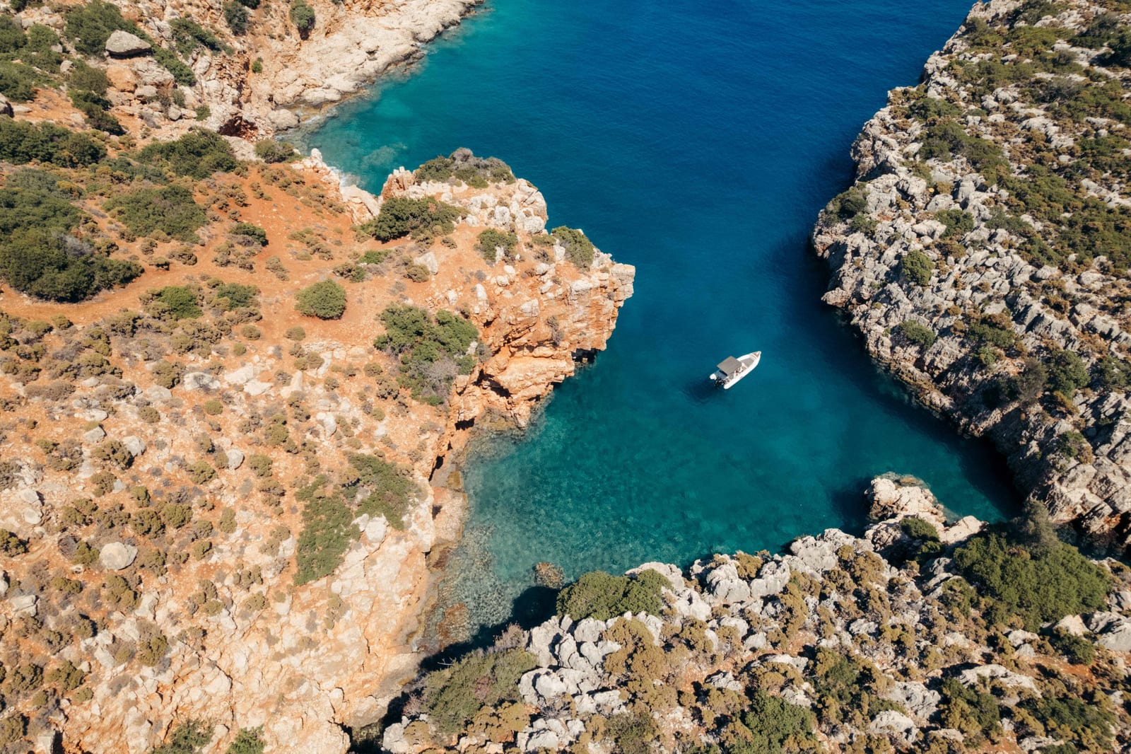 Aerial drone view of Návlakas Bay, with a small boat anchored in turquoise water